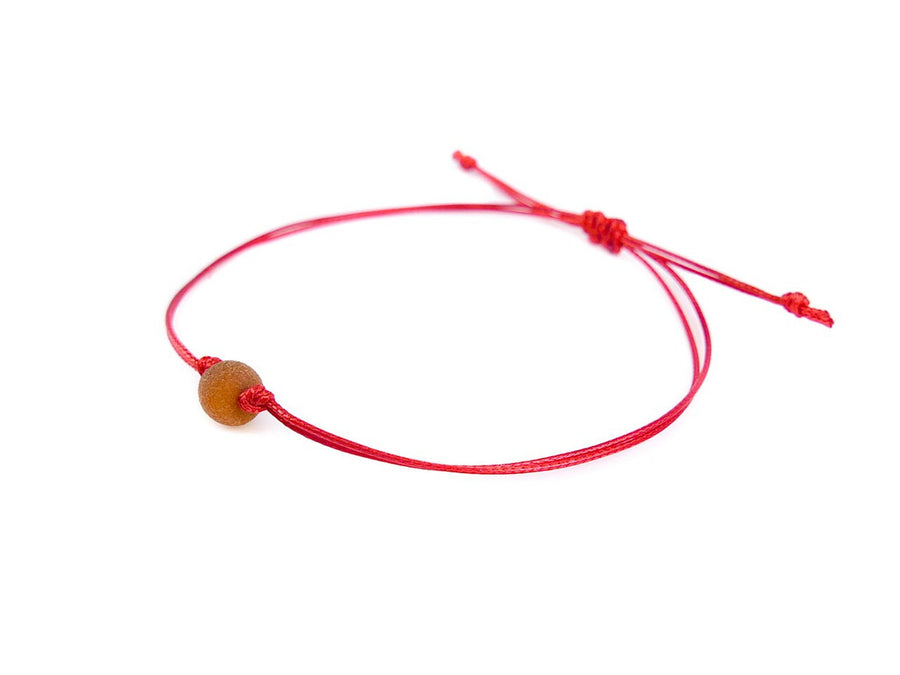 PULSERA DE HILO ROJO CON ÁMBAR BÁLTICO CRUDO EN COLOR COÑAC