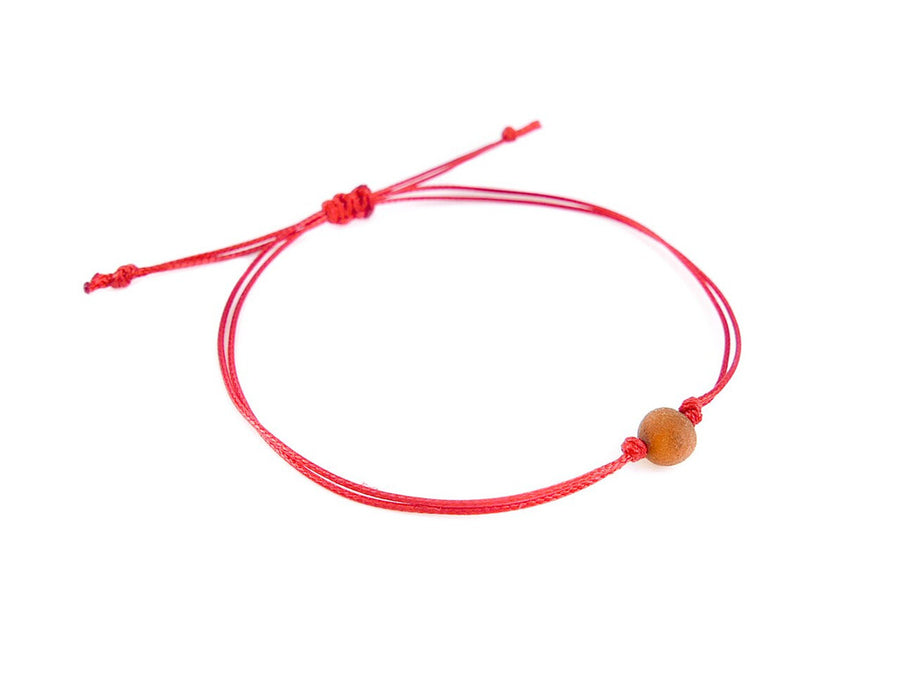 PULSERA DE HILO ROJO CON ÁMBAR BÁLTICO CRUDO EN COLOR COÑAC