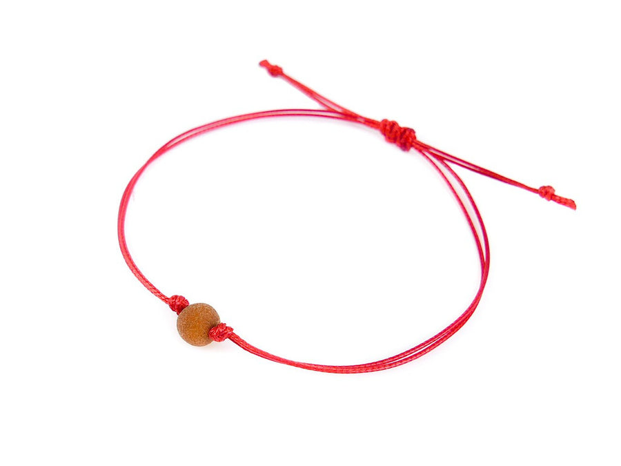 PULSERA DE HILO ROJO CON ÁMBAR BÁLTICO CRUDO EN COLOR COÑAC