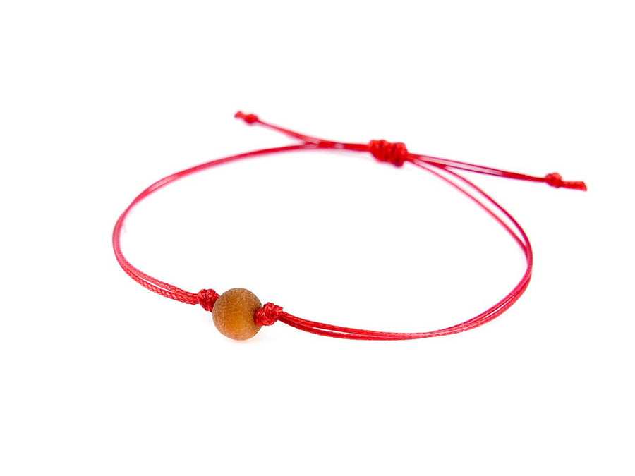 PULSERA DE HILO ROJO CON ÁMBAR BÁLTICO CRUDO EN COLOR COÑAC