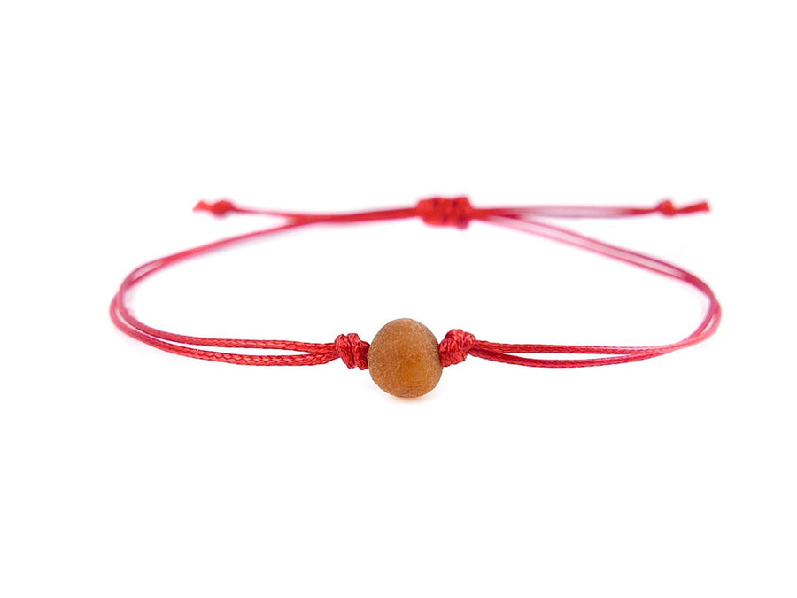 PULSERA DE HILO ROJO CON ÁMBAR BÁLTICO CRUDO EN COLOR COÑAC