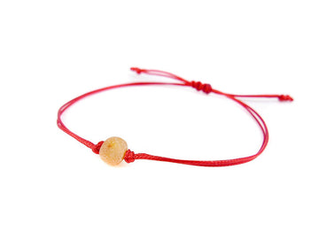 PULSERA DE HILO ROJO CON ÁMBAR BÁLTICO CRUDO EN COLOR MIEL