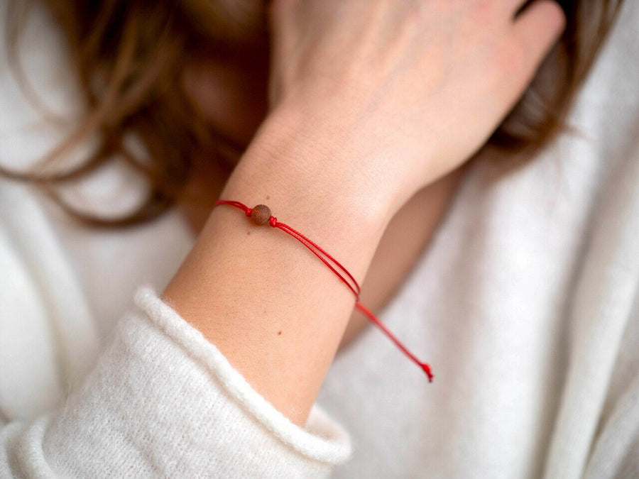 PULSERA DE HILO ROJO CON ÁMBAR BÁLTICO CRUDO EN COLOR COÑAC